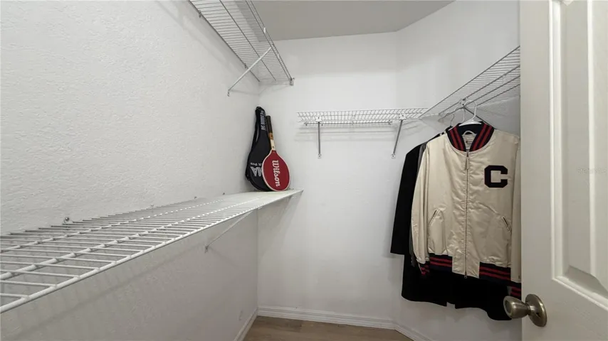 Primary walk-in closet with built-in shelving and hanging storage