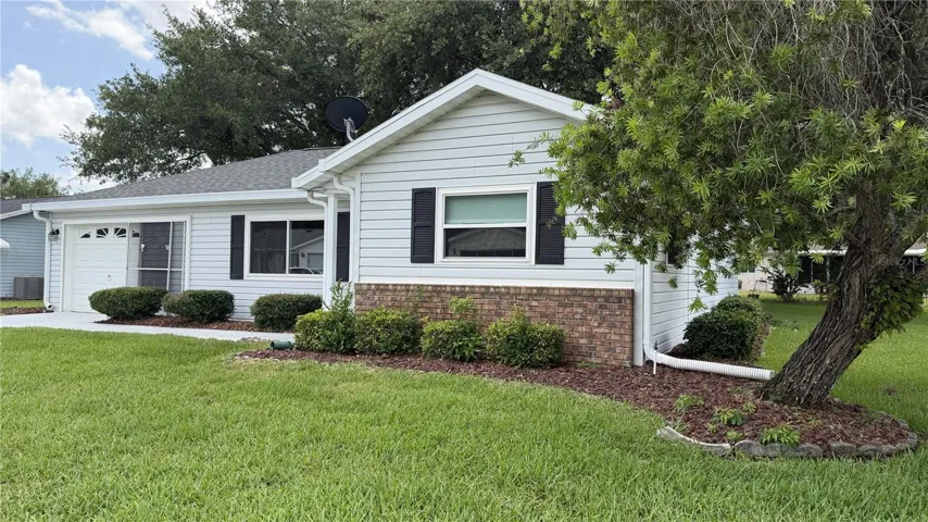 Front exterior landscaping with brick accent and mature shade tree