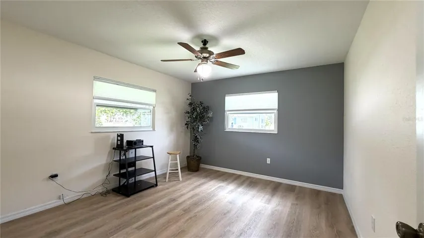 Bedroom 2 with luxury vinyl flooring, ceiling fan, and accent wall