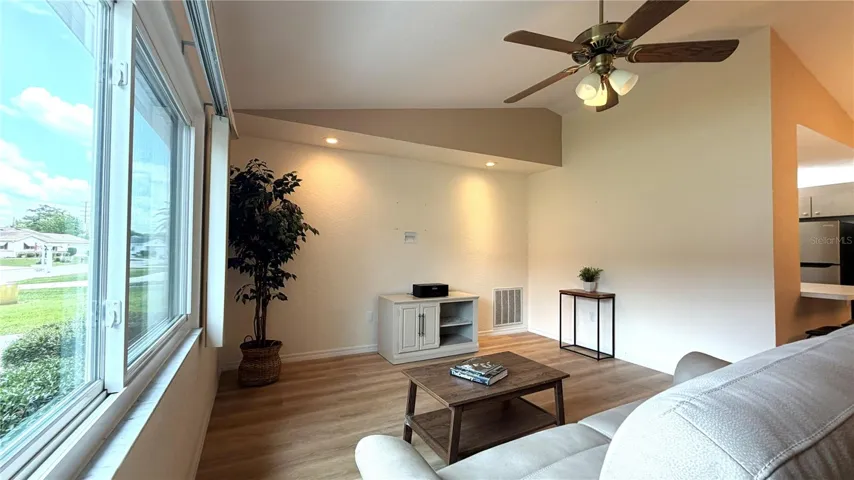 Living room with vaulted ceiling, ceiling fan, and luxury vinyl flooring