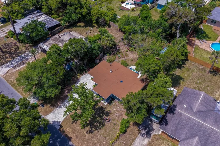 Top-down aerial perspective of the entire property, highlighting the driveway, the rear patio, and the adjacent storage shed.