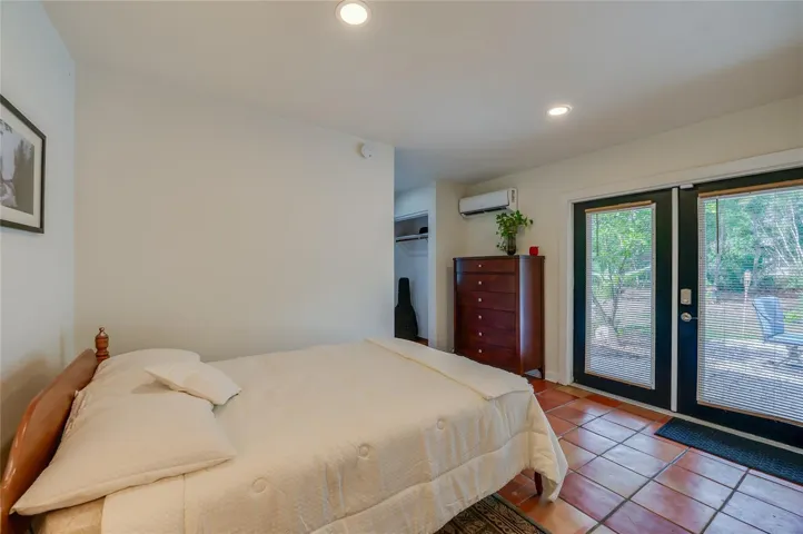 Bright bedroom space with double glass doors that open to the outdoors.
