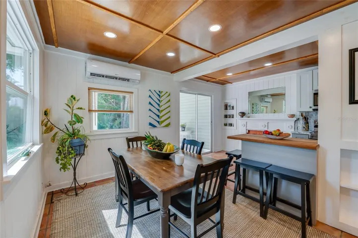 Bright dining area featuring a split-system air conditioner, and a breakfast bar. A sliding glass door provides easy access to the outdoor living space, making it perfect for entertaining.