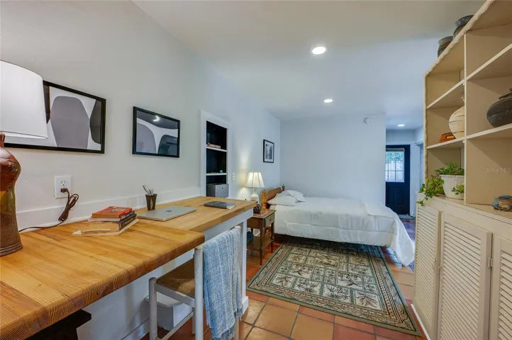 Primary bedroom featuring a built-in wooden desk area. The layout flows toward a back door.