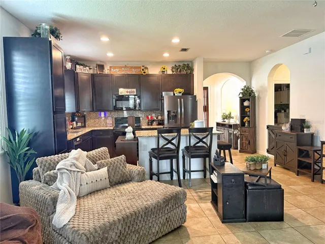 View of the kitchen with 42 inch cabinets, stainless steel appliances, recessed, candle, lighting, kitchen island with bar, top seating, ceramic Tile Flooring, plantation shutters,