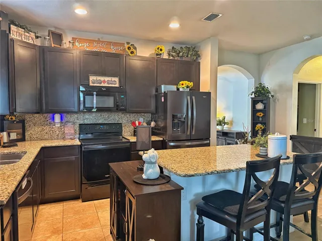 Kitchen with 42” cabinets, granite countertops, island with bar top seating, recessed lighting, stainless steel appliances
