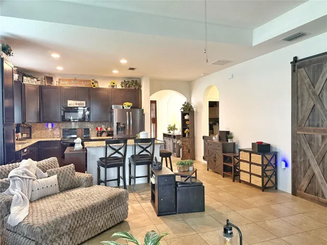 Living room, Kitchen, Barn door entry to Primary bedroom and Entry in background, ceramic tile flooring, recessed lighting