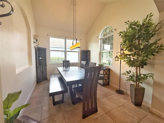 Dining room with ceramic tile flooring, vaulted ceiling, decorative niche
