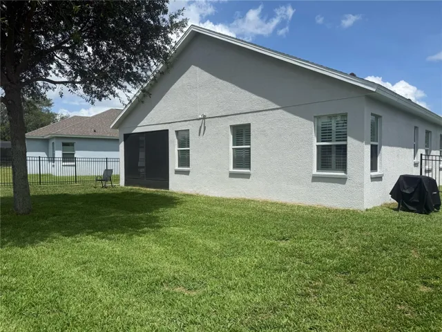 Additional view of the back of the house with the covered and screened in porch and fenced in backyard