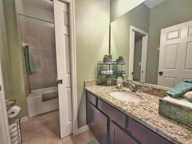 Bathroom two with granite countertops, ceramic tile flooring, tub/shower combo, pocket door into water, closet, and shower area