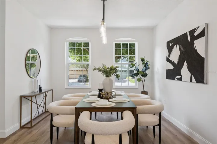 Formal dining area with abundant natural light, contemporary lighting, and wood-look flooring throughout. An inviting space ideal for both everyday meals and special gatherings