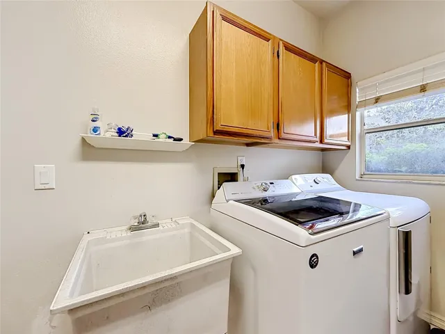 Dedicated indoor laundry room with utility sink and additional storage space