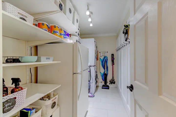 Laundry room with stacked washer and dryer, built-in fridge, utility sink, and tons of storage - all coming wiith the house