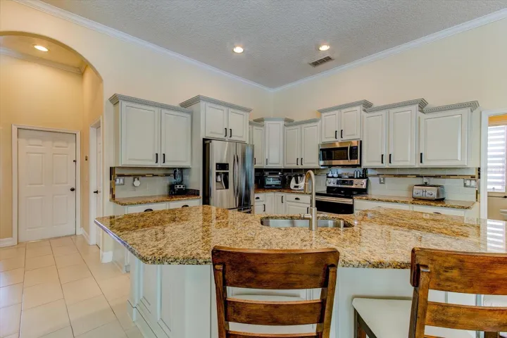 Extensive kitchen with staggered cabinets, custom backsplash, and all stainless steel appliances