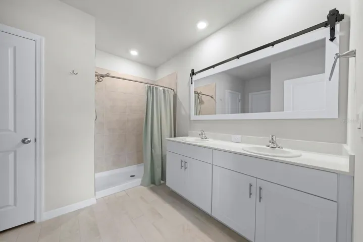 Primary bathroom with walk-in shower, two sinks, and linen closet.