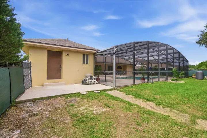 Back yard view of property including pool equipment and door to attached storage area.