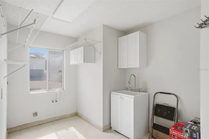 Huge laundry room close to the kitchen with lots of shelving, cabinet space and sink.