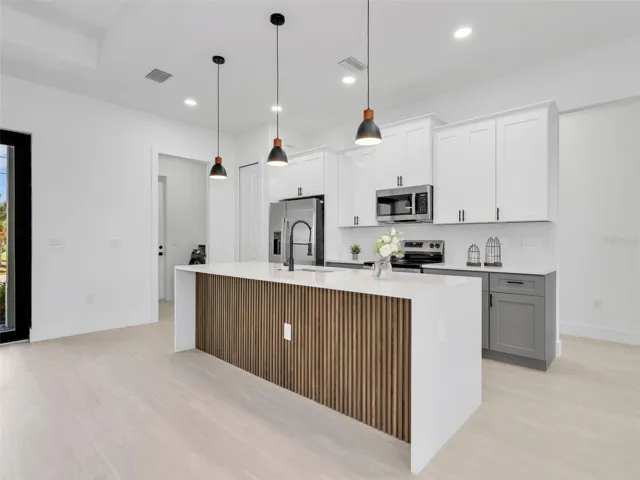 Modern kitchen featuring light wood-finish flooring and a central island with a slatted wood-finish accent panel