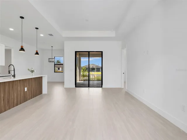 Open concept living space featuring light wood-finish flooring, a contemporary kitchen island with ribbed wood paneling, and modern pendant lighting