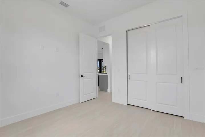 Guest Bedroom featuring light wood-finish flooring, white walls, and white baseboards