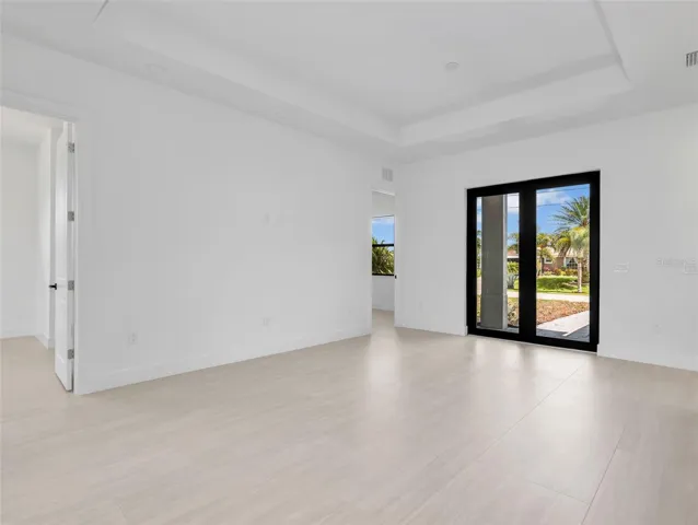 Spacious interior featuring light-toned tile flooring, white walls, and a tray ceiling with recessed lighting