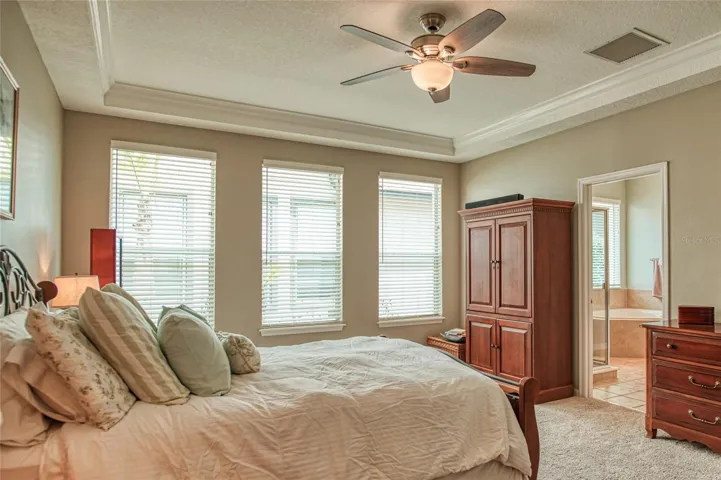 Primary bedroom with tray celing and fan