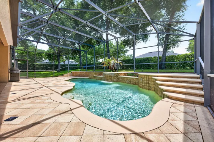Enjoy your own backyard oasis complete with a custom 12,400-gallon screened pool featuring a waterfall, LED color-changing lighting, paver decking, large covered lanai, and plenty of green space for pets, play, or entertaining in the Florida sunshine!