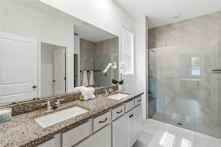 Well-appointed primary bath showcases dual sinks, ample counter space, and a beautifully designed walk-in shower.