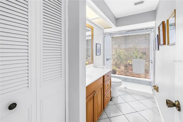Guest bathroom features a unique floor to ceiling glass shower wall.