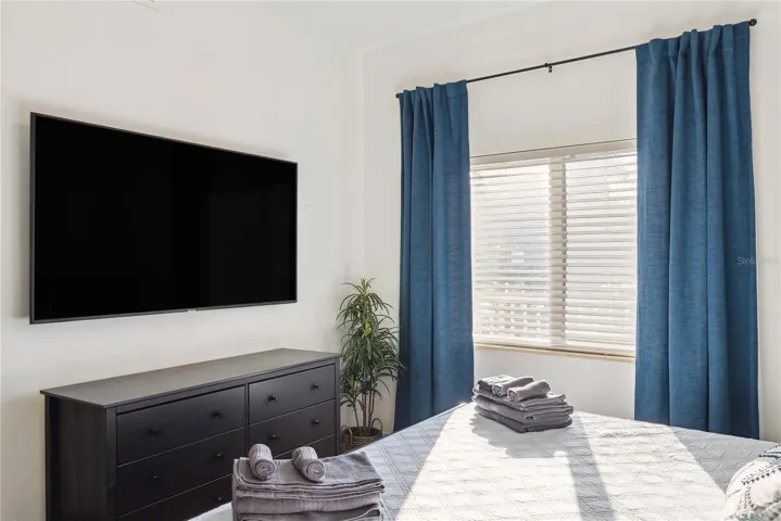 Bedroom with King bed, mounted smart TV, dresser, drapes and decor included