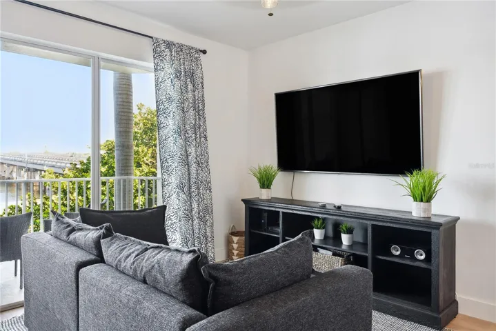 View of Living room with Leather pull-out sleeper sofa, mounted smart TV and storage cabinet, luxury vinyl flooring throughout and custom blackout temperature reducing drapes