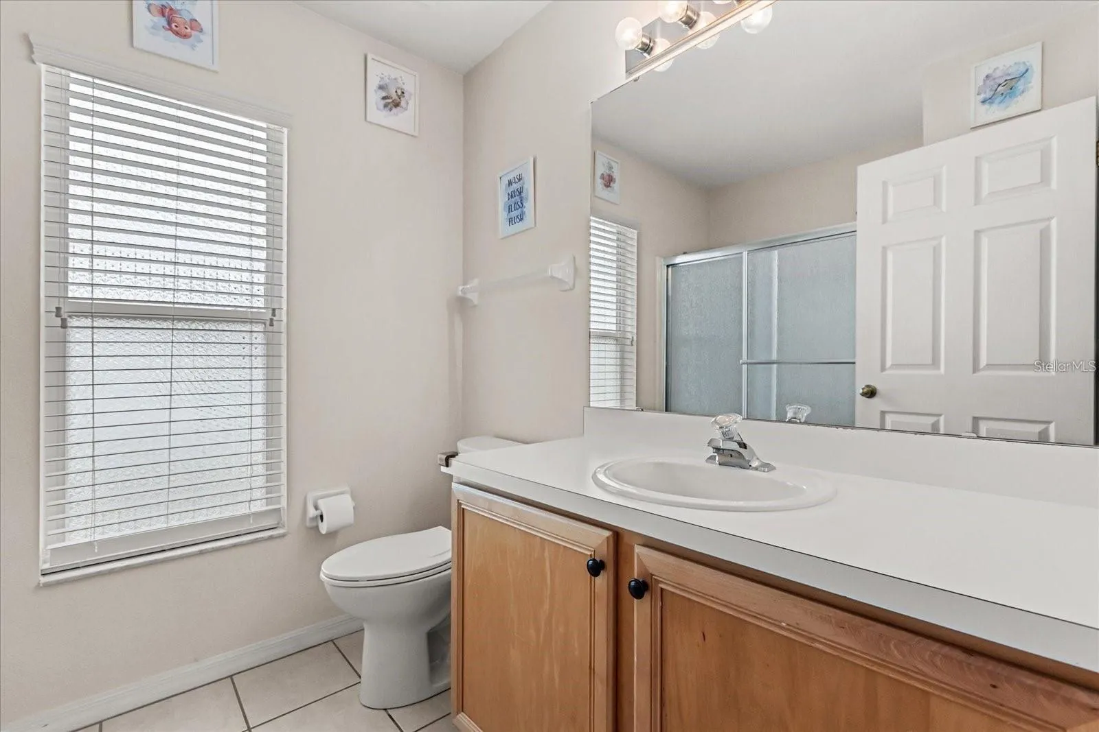 bathroom featuring a single vanity, glass enclosed shower, and natural light from a large window