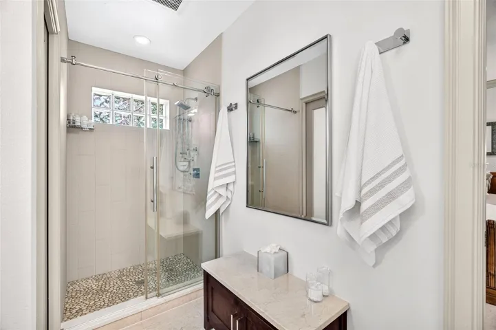Primary with built in lower cabinet & bench seating. Walk in shower with glass enclosure and multi-shower heads.