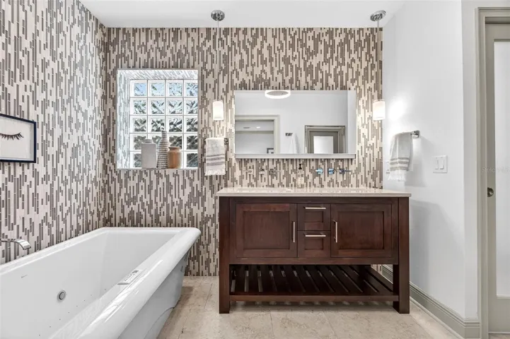 Primary bath with floor to ceiling tile accent walls and dual vanity with uplift vanity mirror and cabinet with integrated electric