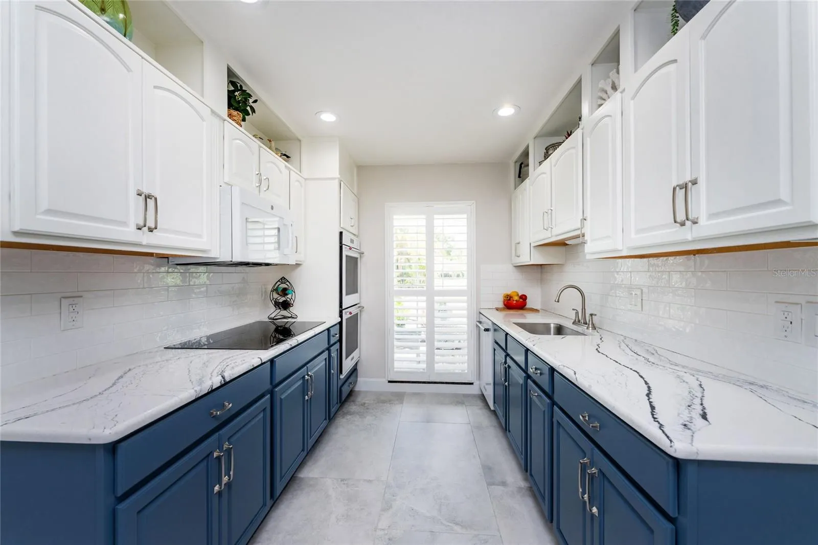 This modern galley style of kitchen offers a sophisticated look with trendy two tone cabinets, high end quartz countertops and subway tile backsplash.