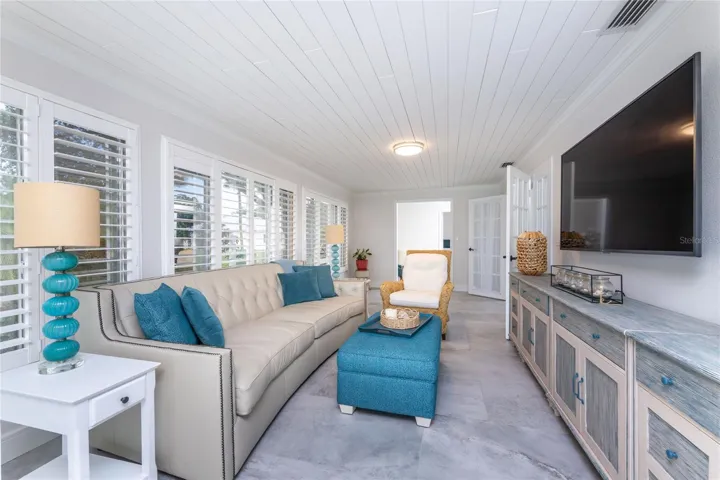 A cozy sunlit family room featuring plantation shutters and a large media console, perfect spot for everyday relaxation.