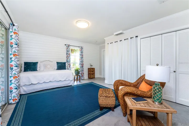 The versatile 3rd bedroom flex room features bright Shiplap style walls and large sliding glass doors that open directly to outdoor lanai