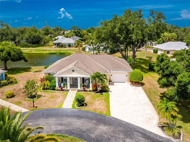 Exceptional curb appeal, a premium water view lot, featuring an inviting columned front porch, manicured tropical landscaping.