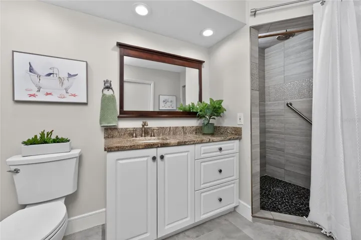 An adjacent guest bathroom offers great functionality with a stone tiled walk in shower and granite countertop vanity