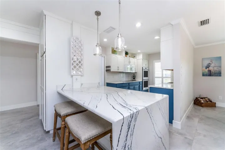 Beautiful updated kitchen features striking quartz countertops with a dramatic waterfall edge island perfect for casual seating.