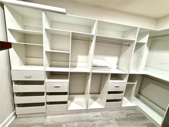 An expansive walk in closet provides a abundance of storage with integrated custom shelving and builtin drawers.