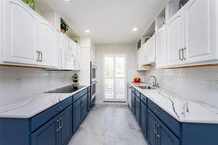 This modern galley style of kitchen offers a sophisticated look with trendy two tone cabinets, high end quartz countertops and subway tile backsplash.