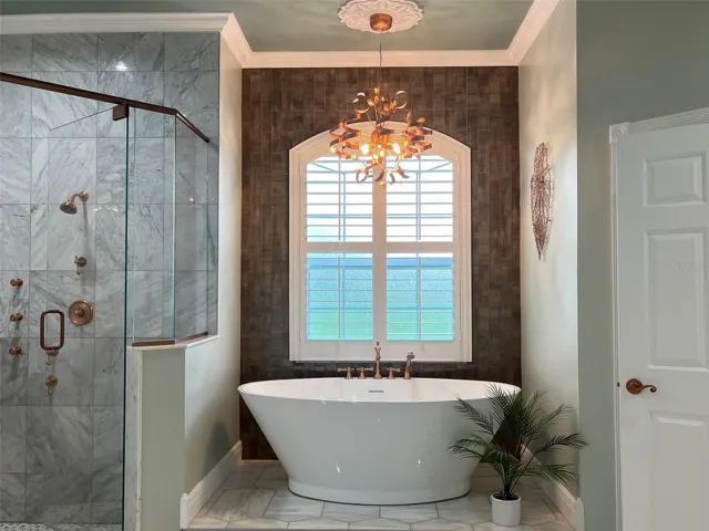 Fully remodeled primary bathroom highlights copper finishes and it is a designers dream.  Such a FUN chandelier over the tub.
