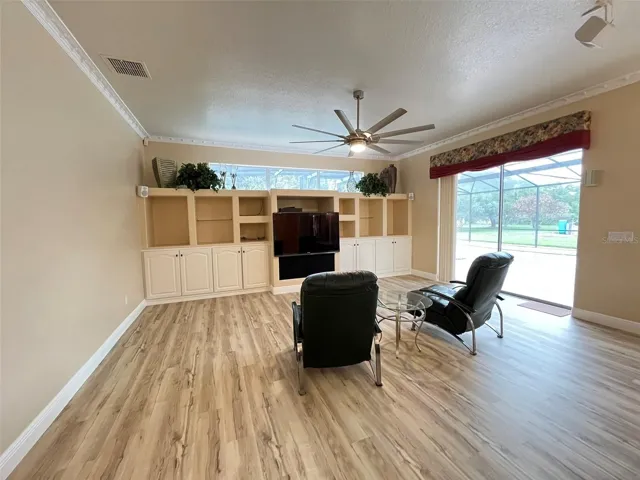 The family room has built in shelves and a built in TV with a large ceiling fan.