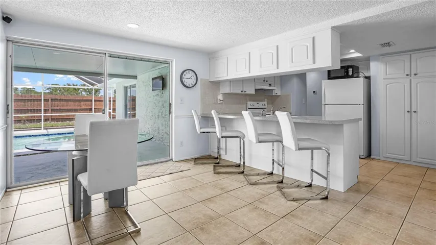 Dining and kitchen overlooking enclosed lanai and pool.