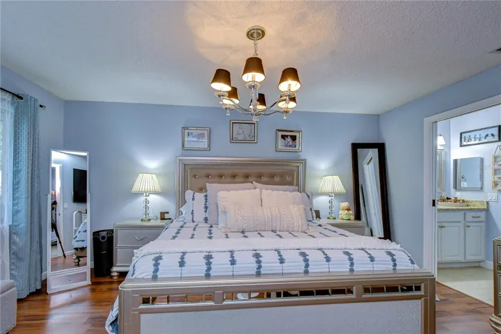Primary bedroom is spacious with inviting lighting and upgraded flooring