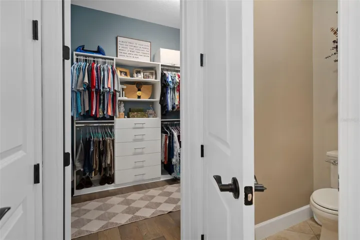 Primary Suite Walk-In Closet with Organizers and a peek a boo view of the Water Closet
