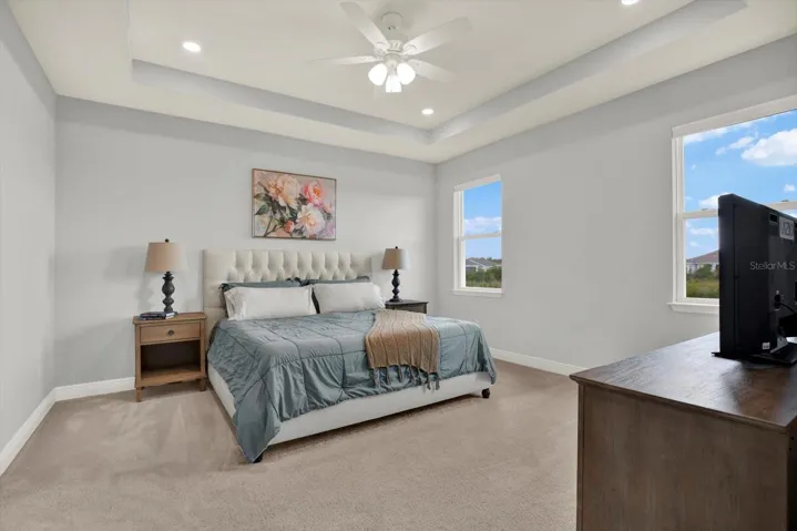 Primary bedroom includes tray ceiling and ceiling fan