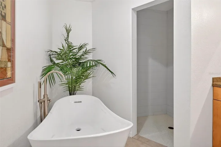 A modern freestanding soaking tub adds a spa-like touch to the primary bath, perfectly paired with the nearby walk-in shower and serene neutral finishes.