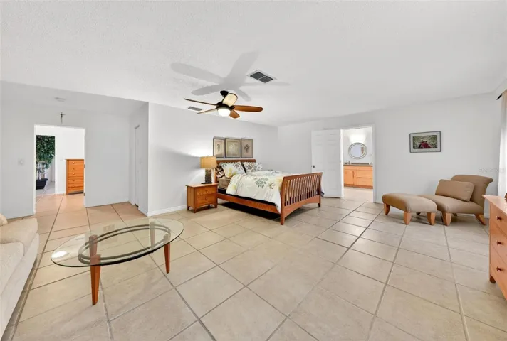 Retreat to a spacious primary suite designed for comfort, privacy, and relaxation, featuring an open layout, room to lounge, and direct access to the en-suite bath — a true owner’s escape within this Lake Dorr home.